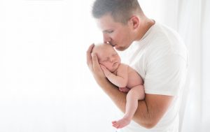 newborn photographer shows dad kissing baby
